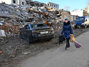 A local resident carries shopping as she walks past a destroyed building following a C-300 missile strike on the Ukrainian city of Kharkiv on March 31, 2023.