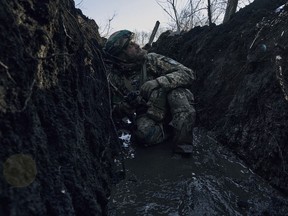 A Ukrainian soldier takes cover in a trench under Russian shelling on the frontline close to Bakhmut, Donetsk region, Ukraine, Sunday, March 5, 2023.