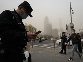 Chinese police officers monitor a junction as a dust storm sweep by in Beijing, Friday, March 10, 2023.