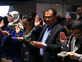 People take the citizenship oath during a special citizenship ceremony at the Canadian Museum of Human Rights in Winnipeg on Dec. 10, 2017.
