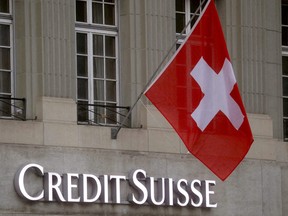 Switzerland's national flag flies above a logo of Swiss bank Credit Suisse in front of a branch office in Bern, Switzerland, Nov. 29, 2022.
