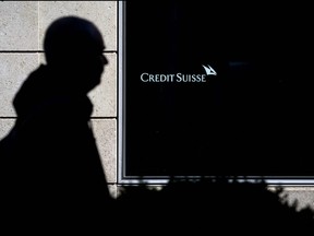 A man is seen in silhouette walking past a branch of Switzerland's Credit Suisse bank in Vevey, western Switzerland, on March 15, 2023.