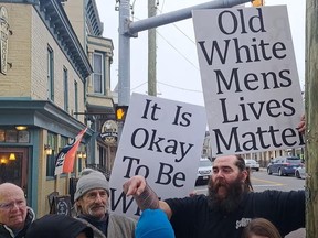 Men holding signs that read "It Is Okay To Be White" and "Old White Mens Lives Matter" at protest