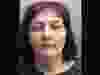 Mugshot of woman with reddish-purple hair.