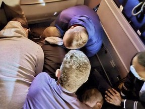 This image provided by Simik Ghookasian shows passengers and crew members restraining a man who according to federal authorities tried to open an airliner's emergency door and tried to stab a flight attendant on a weekend flight from Los Angeles to Boston on Sunday, March 5, 2023.