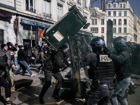 A policeman is hit with a bin as, demonstrators clash with police in Lyon, central eastern France, during protests on the 8th day of strikes and protests across the country against the government's proposed pensions overhaul on March 15, 2023.