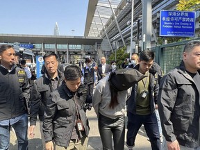 In this photo released by Hong Kong's Information Services Department, Hong Kong police escort a suspect at the Shenzhen Bay Port border crossing in Hong Kong, Tuesday, March 7, 2023.