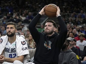 Dallas Mavericks guard Luka Doncic, right, returns the ball to play as he sits on the bench during the first half of an NBA basketball game against the San Antonio Spurs in San Antonio, Wednesday, March 15, 2023.