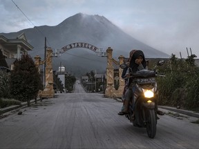 A motorcyclist wearing a mask rides past in an area covered by ash after Mount Merapi erupted spewing volcanic materials at Stabelan village on March 11, 2023 in Boyolali, Central Java, Indonesia.