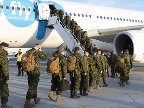 Members of the 5e Regiment d'artillerie legere du Canada board an aircraft heading for Latvia, in Quebec City, Wednesday, March 23, 2022.