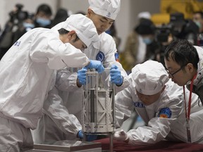 In this Dec. 17, 2020 photo provided by China's Xinhua News Agency, technicians prepare to weigh a container carrying moon samples retrieved by China's Chang'e 5 lunar lander in Beijing.