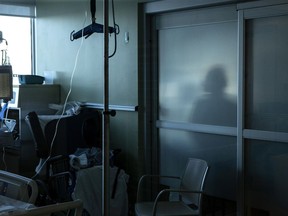 A nurse is silhouetted behind a glass panel as she tends to a patient in the Intensive Care Unit at an Ontario hospital, on Tuesday, January 25, 2022.