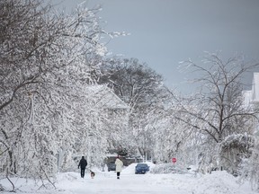 People walk along an ice covered street after a winter storm in Fort Erie, Ont., Tuesday, Dec. 27, 2022.&ampnbsp;Nearly two dozen small municipalities in Ontario will share $5.5 million to help with recovering from extreme weather.