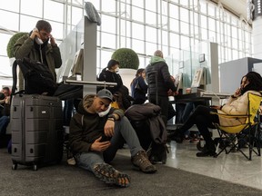 Travellers wait on hold as they try and speak with their respective airlines at Toronto Pearson International Airport, as a major winter storm disrupts flights in and out of the airport in Toronto, Dec. 24, 2022.