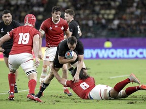 New Zealand's Ben Smith attempts to evade the tackle of Canada's Tyler Ardron, right, and Mike Sheppard, left, during the Rugby World Cup Pool B game at Oita Stadium between New Zealand and Canada in Oita, Japan, Wednesday, Oct. 2, 2019.