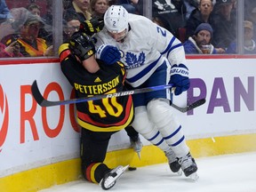 Elias Pettersson of the Vancouver Canucks is checked by Luke Schenn of the Toronto Maple Leafs at Rogers Arena on March 4, 2023 in Vancouver.