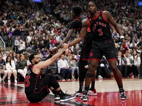 Fred VanVleet of the Toronto Raptors is helped up by teammates Chris Boucher and O.G. Anunoby.