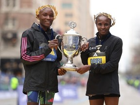 Evans Chebet of Kenya and Hellen Obiri of Kenya pose with the trophy on the finish line after winning the professional Men's Division and professional Women's Division respectively during the 127th Boston Marathon on April 17, 2023 in Boston, Massachusetts.