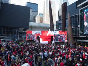 Fans watch NBA playoff game action between the Toronto Raptors and the Philadelphia 76ers at a closed-off tailgate area outside the Scotiabank Arena known as Jurassic Park in Toronto on Saturday, April 16, 2022.