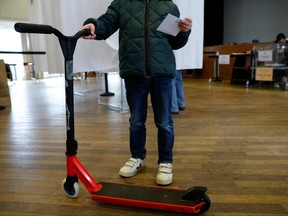 A person holds a ballot and an e-scooter during a municipal public "citizen vote" voting session on free-floating electric scooters at the city hall of the 17th district in Paris on April 2, 2023.