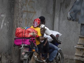 Residents travel on a motorbike as they flee their home to avoid clashes between armed gangs, in the Croix-des-Mission neighbourhood of Port-au-Prince, Haiti, Thursday, April 28, 2022.