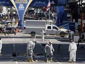 Investigators sift through evidence on Boylston Street, just up from the finish line of the Boston Marathon in Boston, Thursday, April 18, 2013.