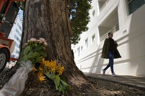 A woman walks past flowers left outside an apartment building where technology executive Bob Lee was fatally stabbed in San Francisco, Wednesday, April 5, 2023.