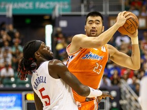 Zhang Zhaoxu of the Shanghai Sharks looks to pass the ball as he is guarded by Montrezl Harrell of the Los Angeles Clippers during the first half of the game at the Stan Sheriff Center on October 6, 2019 in Honolulu, Hawaii.