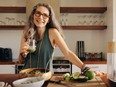 Healthy older woman smiling while holding some green juice in her kitchen.