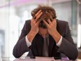 Frustrated businessman sitting at desk with  head in hands