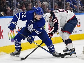 Apr 4, 2023; Toronto, Ontario, CAN; Toronto Maple Leafs defenseman Jake McCabe battles with Columbus Blue Jackets forward Eric Robinson for the puck during the second period at Scotiabank Arena.