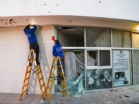 People work outside a damaged building after rockets from Lebanon were fired into Israel, in Shlomi, northern Israel, April 6, 2023.