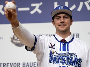 Trevor Bauer with his new uniform and cap of Yokohama DeNA BayStars poses for photographers during a photo session of the news conference, March 24, 2023, in Yokohama, near Tokyo.