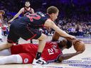 Joel Embiid #21 of the Philadelphia 76ers battles from the floor for the ball with Malachi Flynn #22 of the Toronto Raptors.