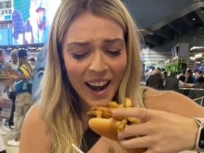 Jordan Cicchelli takes a bite out of a poutine hot dog at Rogers Centre on April 11, 2023.