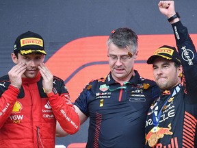 Winner Red Bull Racing's Mexican driver Sergio Perez celebrates on the podium next to third placed Ferrari's Monegasque driver Charles Leclerc after the Formula One Azerbaijan Grand Prix at the Baku City Circuit in Baku on April 30, 2023.