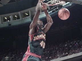 Shawn Kemp of the Seattle Supersonics hangs on the basket following a slam dunk during NBA action against the Vancouver Grizzlies in Vancouver, Feb. 18, 1996.