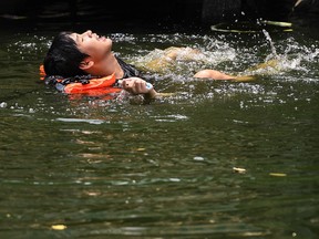 A man swims in a canal as temperatures hit a record 45.4C in Bangkok, Thailand, April 22, 2023.