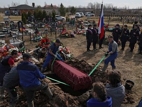 Workers lower the coffin during a funeral of Russian army Lieutenant Colonel Andrey Savinov in the town of Kirishi in the Leningrad region, Russia April 11, 2023.