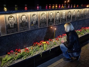 A woman prays at a memorial dedicated to firefighters and workers who died after the Chornobyl nuclear disaster, during a night commemorative service, amid Russia’s attack on Ukraine, in Slavutych, Ukraine, on April 26, 2023.