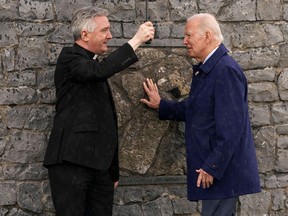U.S. President Joe Biden touches the original gable wall of the church at the Knock Shrine, with Father Richard Gibbons, in County Mayo, Ireland, April 14, 2023.