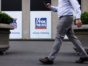 A person walks by Fox News signage posted on the News Corporation building in New York City, April 12, 2023.