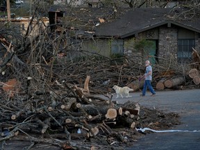 A man walks a dog through a neighbourhood severely damaged in the aftermath of a tornado, after a monster storm system tore through the South and Midwest on Friday in Little Rock, Ark., April 1, 2023.