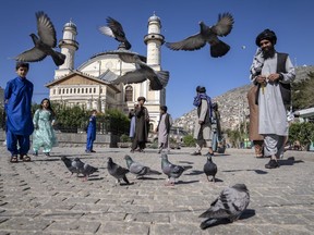 Afghan people walk pass the Shah-Do Shamshira Mosque during the first day of Eid al-Fitr in Kabul, Afghanistan, Friday, April 21, 2023.
