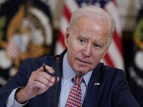 President Joe Biden adjusts his microphone during a meeting with the President's Council of Advisors on Science and Technology in the State Dining Room of the White House, Tuesday, April 4, 2023, in Washington.