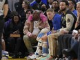 E-40, middle, watches during an NBA basketball game between the Golden State Warriors and the Portland Trail Blazers in San Francisco, Dec. 30, 2022. The Sacramento Kings are investigating allegations from the rapper E-40 that "racial bias" led to him being kicked out of his seat during a playoff game against the Golden State Warriors. E-40 said in a statement that he was heckled throughout the game Saturday, April 15, 2023, night and addressed one heckler "in an assertive but polite manner" before security guards came and ordered him to leave the arena.