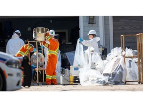 Workers from waste management company GFL Environmental Inc. bag laboratory equipment at the alleged marijuana processing lab found in a high-end Commissioners Road home in London. Photograph taken on Monday April 10, 2023. (Mike Hensen/The London Free Press)