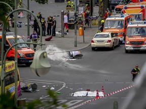 A covered body, foreground, lies on the street after a car crashed into a crowd of people in central Berlin, Germany, June 8, 2022. A German court has convicted a 30-year-old man who drove into groups of pedestrians in Berlin last year of one count of murder and 16 counts of attempted murder, ordering him to be permanently held in a psychiatric hospital.