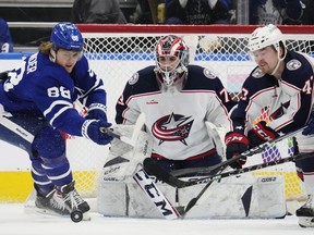 Maple Leafs' William Nylander (left) and Columbus Blue Jackets' Marcus Bjork battle for the puck as goaltender Jet Greaves looks on during the first period in Toronto on Tuesday, April 4, 2023.