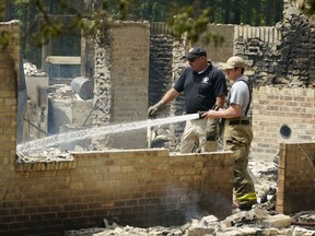 A member of the Mississippi State Fire Marshal's Office, left, waits as a firefighter waters down hot spots inside a burned out house, Wednesday morning, April 26, 2023, in Conway, Miss.
